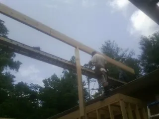 Carpenter setting a ridge beam over a new addition frame — Ice Dam Removal by Roofing Brothers in Princeville
