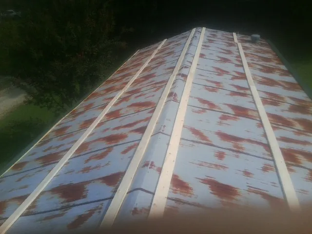 Rusted metal roof panels with new wood purlins before replacement — Storm Damage Roof Repair in Princeville by Roofing Brothers