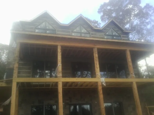Dormers and porch framing on a large log home under construction — Roof Coating work by our crew in Princeville