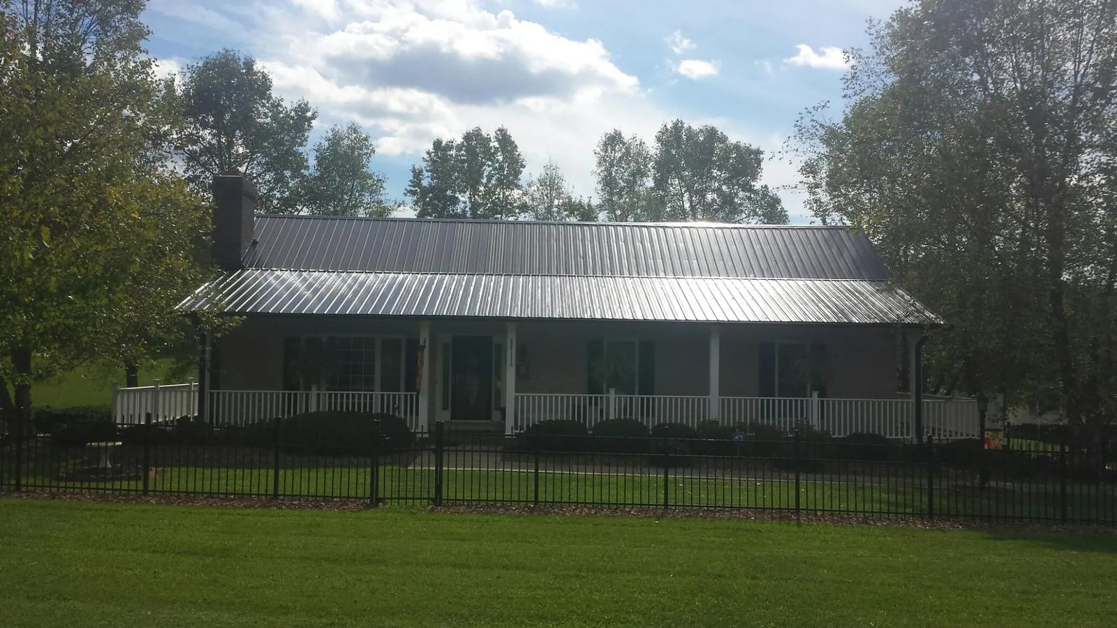 Gray metal roof on a brick ranch with a full width front porch — Gutter Guard Installation work by our crew in Princeville