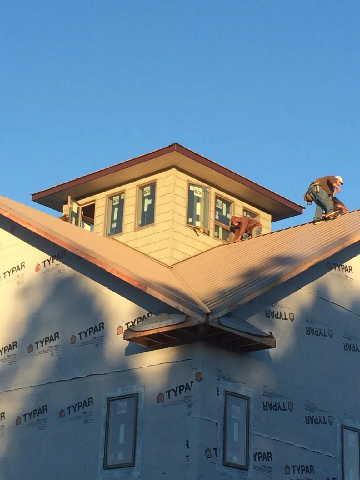 Roofers working around a rooftop cupola on a new metal roof at sunset — Roof Waterproofing in Princeville by Roofing Brothers